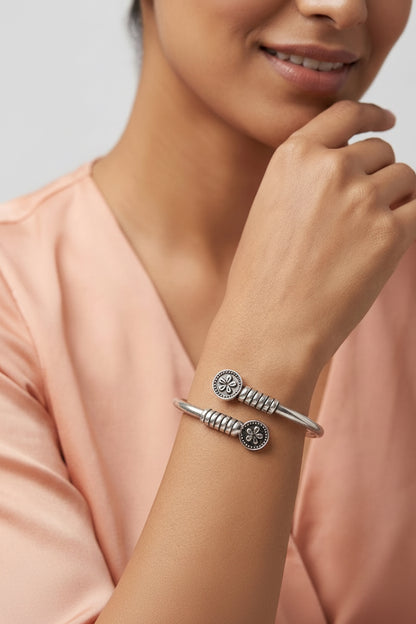 Silver bracelet on a wrist with a neutral background